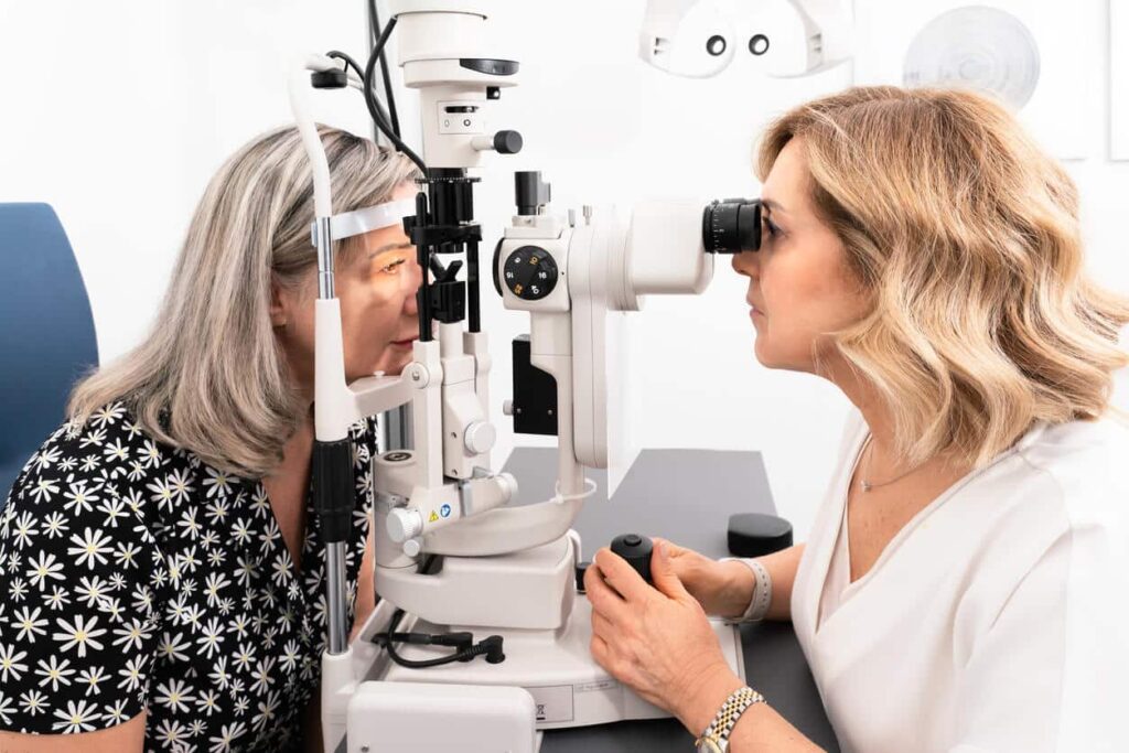 Older woman getting an eye exam with a slit-lamp machine
